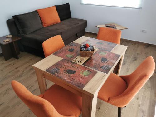 a dining room table with orange chairs and a couch at Iznad oblaka A1 in Kopaonik