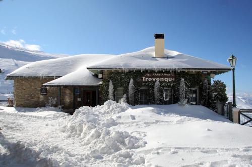 a building covered in snow with a pile of snow at Hotel Apartamentos Trevenque in Sierra Nevada