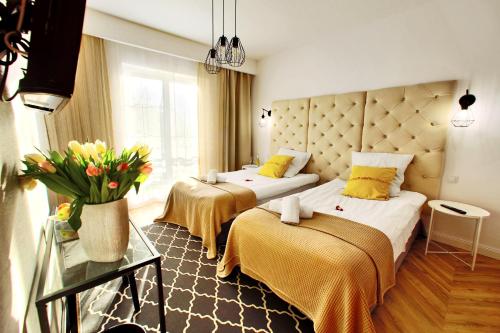 a hotel room with two beds and a vase of flowers at Rezydencja Pod Tężnią & SPA in Inowrocław