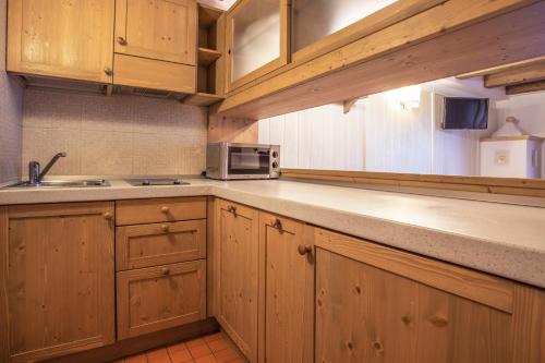 a kitchen with wooden cabinets and a microwave at Al Sole Clubresidence in Canazei