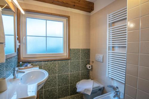 a bathroom with a sink and a window and a toilet at Al Sole Clubresidence in Canazei