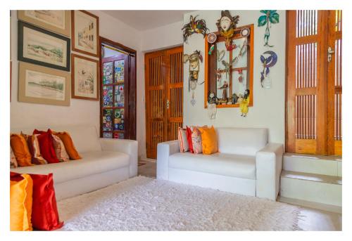 a living room with two white couches with colorful pillows at Pousada Cravo e Canela in Arraial d'Ajuda