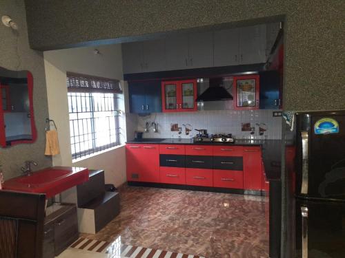 a kitchen with red cabinets and a red sink at Srinikethana Home Stay with Swimming Pool in Madikeri