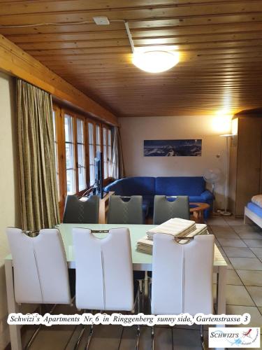 a dining room table with chairs and a blue couch at Schwizi's Apartments in Ringgenberg