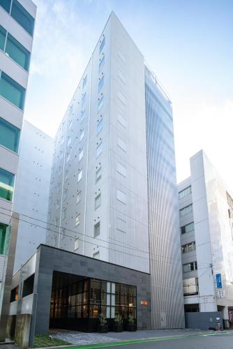 a tall white building with a lot of windows at HOTEL FORZA HAKATAEKI CHIKUSHIGUCHI Ⅱ in Fukuoka