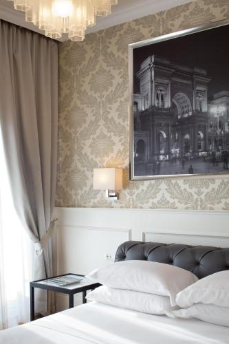 a bedroom with a bed with a picture on the wall at Suite Milano Duomo in Milan
