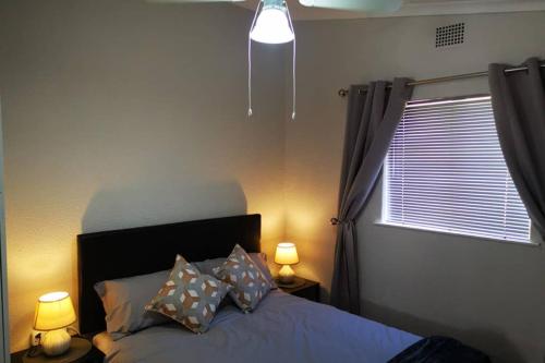 1 dormitorio con 1 cama con 2 lámparas y una ventana en The Smiths Self Catering Cottage, en Ciudad del Cabo