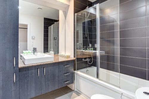 a bathroom with a tub and a sink and a shower at Les Immeubles Charlevoix - Le 1174 in Quebec City