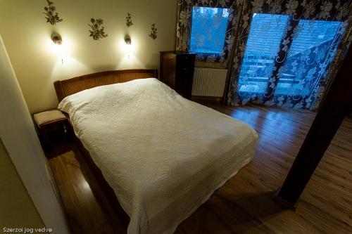 ein Schlafzimmer mit einem weißen Bett und einem Fenster in der Unterkunft Balázs Szálló in Gyula