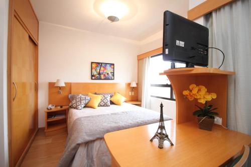 een slaapkamer met een bed en een televisie op een bureau bij Flat 4 Estrelas Jardins in Sao Paulo