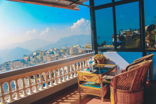 een tafel en stoelen op een balkon met uitzicht bij Horizon Homestay in Tānsen