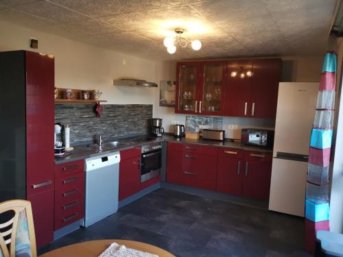 a kitchen with red cabinets and a white refrigerator at Haus Kunterbunt in Mehlingen