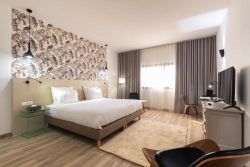 ダカールにあるHotel L'Adresse Dakarのベッドとテレビが備わるホテルルームです。