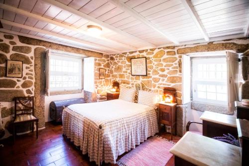 a bedroom with a bed and a stone wall at Casa do Tamanqueiro in Ponte de Lima