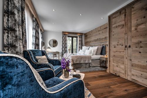 a bedroom with a bed and two blue chairs at Hôtel La Sivolière in Courchevel