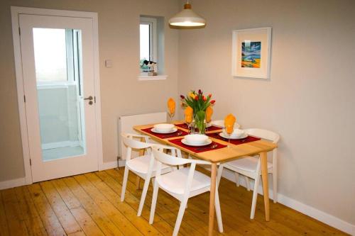 Park House في Port of Ness: غرفة طعام مع طاولة مع كراسي وورود عليها