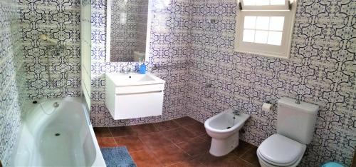 ein Badezimmer mit einer Badewanne, einem WC und einem Waschbecken in der Unterkunft Casa Arcanjo in Lagoa