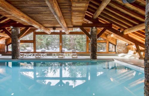 a pool in a house with wooden ceilings at Résidence Pierre & Vacances Premium Les Fermes De Méribel in Méribel