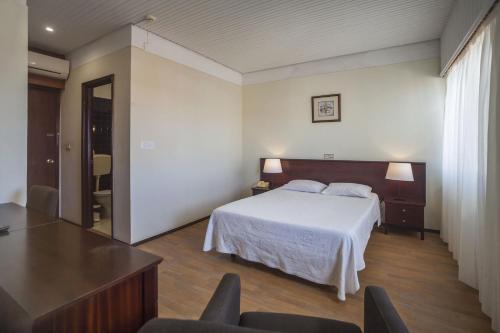 1 dormitorio con 1 cama, mesa y sillas en Hotel Sete Cidades, en Ponta Delgada