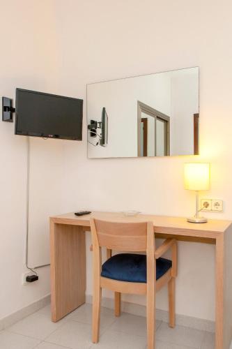 a desk with a lamp and a mirror on a wall at Hotel Ibiza Playa in Ibiza Town