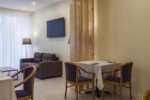 a dining room with a table and chairs and a couch at Hotel Sete Cidades in Ponta Delgada