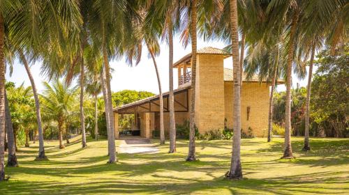 a building with palm trees in front of it at Refúgios Parajuru - Villa Cristiano in Parajuru