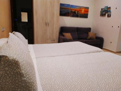 a white bed in a room with a couch at Hostal Casa Nautilus in Cádiz