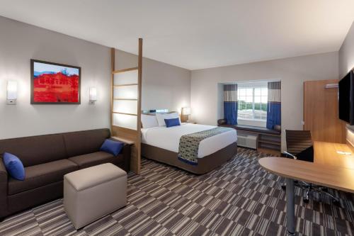 カレッジ・ステーションにあるMicrotel Inn & Suites by Wyndham College Stationのベッドとソファ付きのホテルルーム
