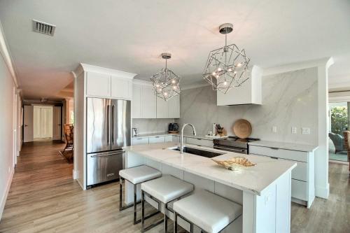 a kitchen with white cabinets and a kitchen island with stools at Lavish Vero Beach Escape with Pool, Patio and Dock! in Vero Beach