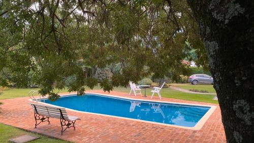 a swimming pool with a bench and a table and chairs at Ruda Lodge Exclusive Bed & Breakfast in General Rodríguez