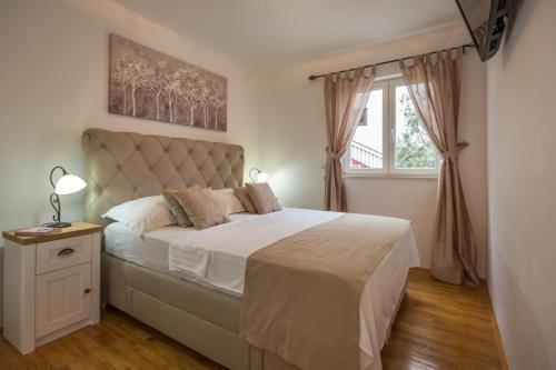 ein Schlafzimmer mit einem großen Bett und einem Fenster in der Unterkunft Apartments Royal Residence in Baška Voda