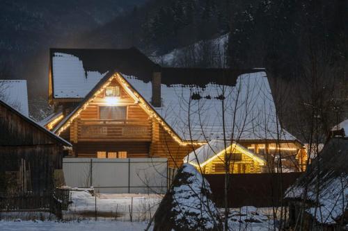 a log cabin with a light on it in the snow at Sadyba Pikuy in Bilasovytsya