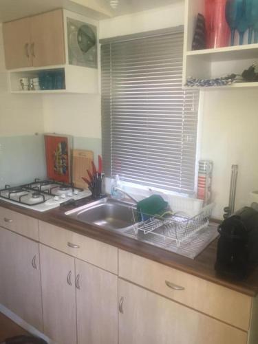 un comptoir de cuisine avec un évier et une fenêtre dans l'établissement Mobil home climatisé, bord de mer Macinaggio, à Macinaggio