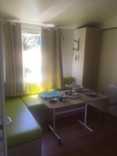un salon avec une table et une fenêtre dans l'établissement Mobil home climatisé, bord de mer Macinaggio, à Macinaggio