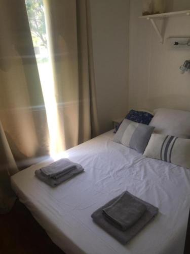 - un lit avec 2 serviettes et une fenêtre dans l'établissement Mobil home climatisé, bord de mer Macinaggio, à Macinaggio