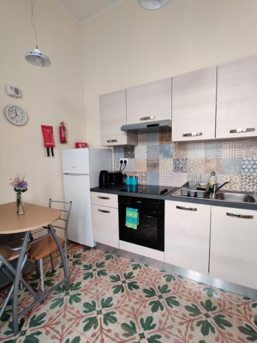a kitchen with white cabinets and a table and a sink at Ellas Place in Tarxien
