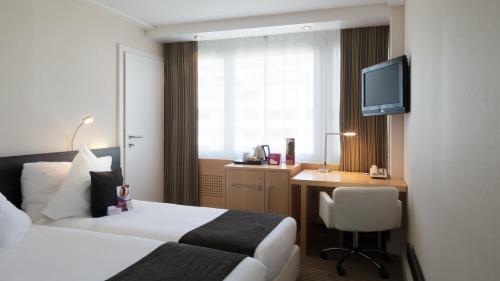a hotel room with a bed and a desk and a television at Crowne Plaza Zürich by IHG in Zürich