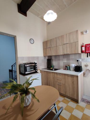 a kitchen with wooden cabinets and a table with a plant at Rons Town House in Tarxien