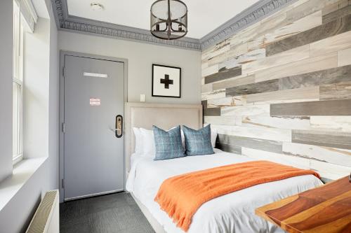 1 dormitorio con cama y pared de madera reciclada en Sonder The Wellesley, en Toronto