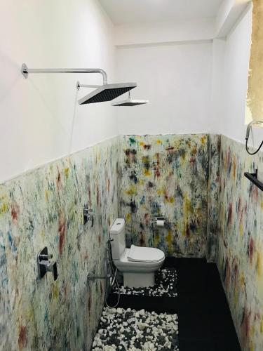 a bathroom with a toilet and a painting on the wall at The Hobbit Cottage-Ella in Ella
