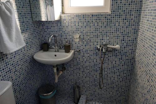 een blauw betegelde badkamer met een wastafel en een toilet bij Psychiko's View in Athene