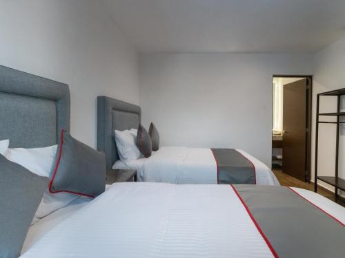 two beds in a hotel room with white sheets at Fraga Hotel Boutique in Irapuato