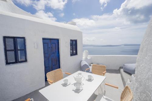 uma mesa branca e cadeiras numa varanda com o oceano em Canvas Suites em Oia