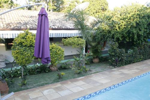 a purple umbrella sitting next to a swimming pool at Pousada do Marujo in Rio das Ostras