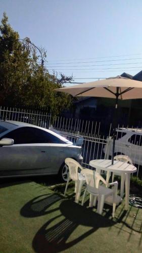 einen Tisch und Stühle, einen Regenschirm und ein Auto in der Unterkunft Alojamiento en Chillán in Chillán