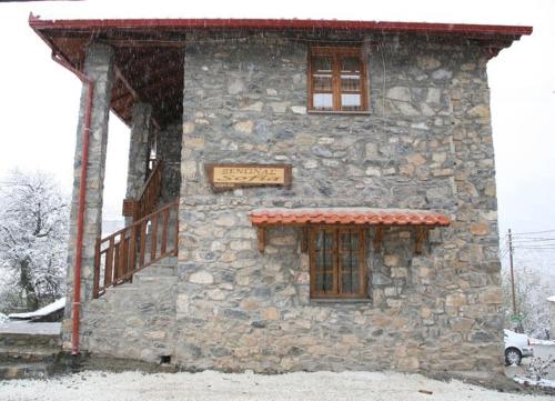a stone building with a sign on it in the snow at Guesthouse Sofia in Palaios Agios Athanasios