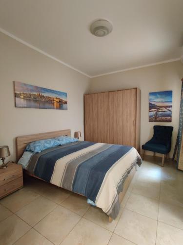 um quarto com uma cama grande e uma cadeira azul em Doms Apartment em Tarxien