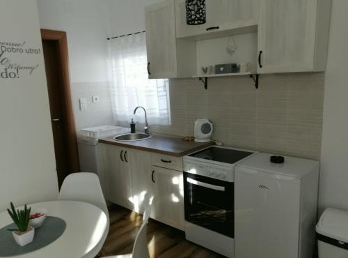 una pequeña cocina con armarios blancos y fregadero en Apartman Gušt en Herceg-Novi