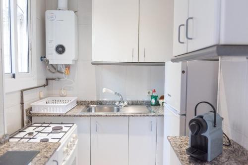 a white kitchen with a sink and a stove at Sweet BCN Studio with Terrace in Barcelona