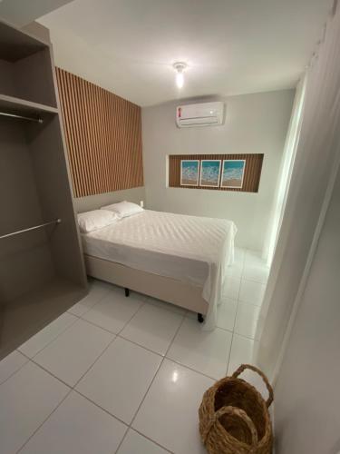 a small bedroom with a bed and a basket at Portal do Atlântico in Barra de São Miguel